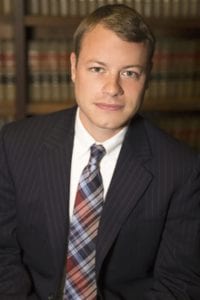 David Dobson, WV injury attorney in front of stack of law books