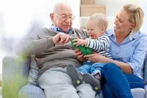 senior man with mesothelioma sitting with his daughter and grandson on sofa - Indoors