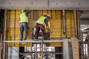 Two construction workers working on a scaffolding platform