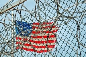 US flag behind prison fence and barb wire