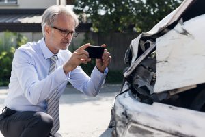 WV car accident insurance adjuster taking photos of damage to the car.