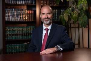 WV personal injury lawyer and West Law Firm founder Brooks West sitting in front of law books at his office in Charleston, WV