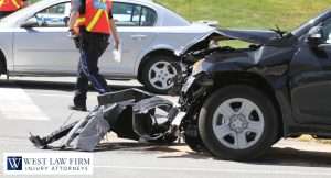 Damaged vehicle after a car accident with police on scene, showing debris and front-end damage for a personal injury claim